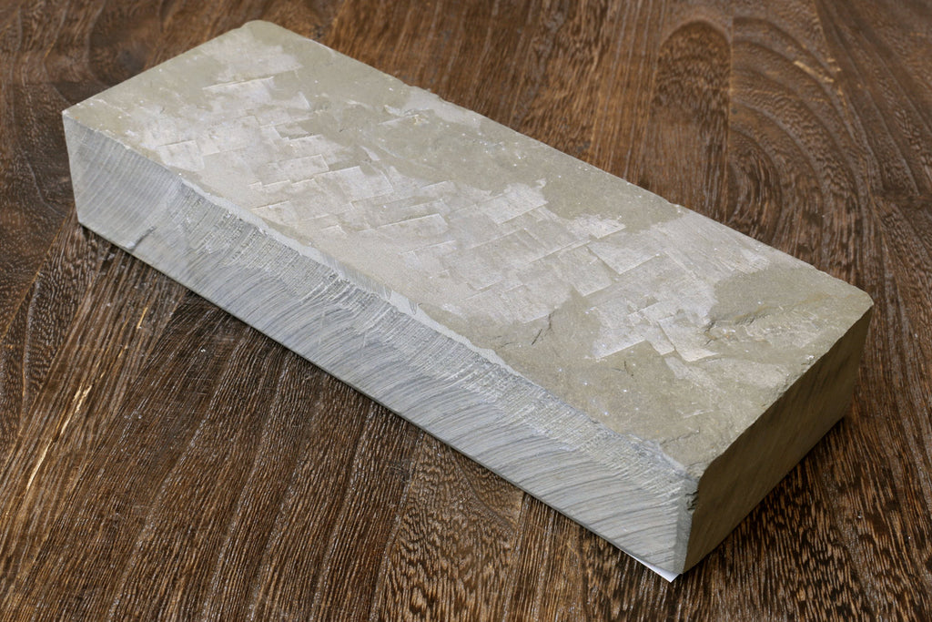 Natural whetstone finishing stone, off-white rectangular block with striated texture