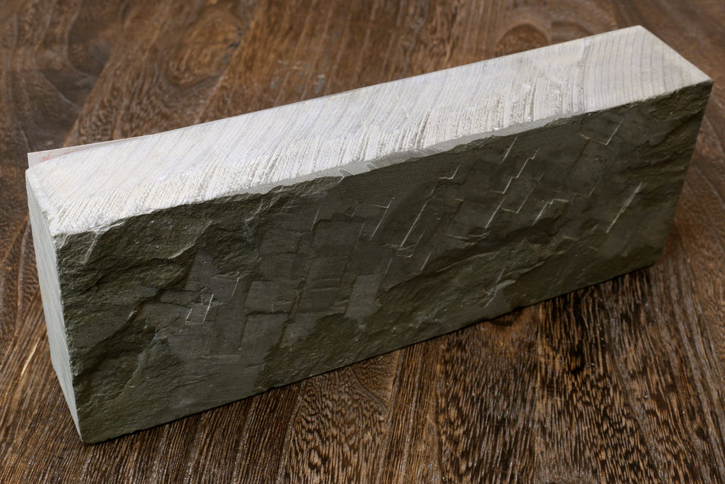 Natural whetstone finishing stone, dark grey rectangular block with striated texture