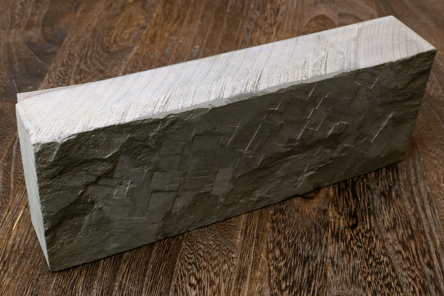 Natural whetstone finishing stone, dark grey rectangular block with striated texture
