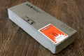 Whetstone sharpening stone, light gray rectangular block with paper labels on side