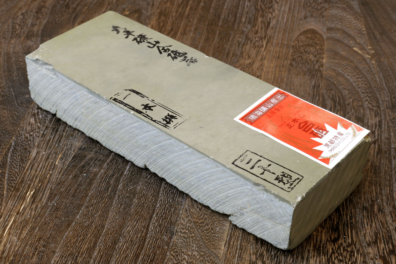 Sharpening whetstone block with paper label and red seal on one side, white-edged.