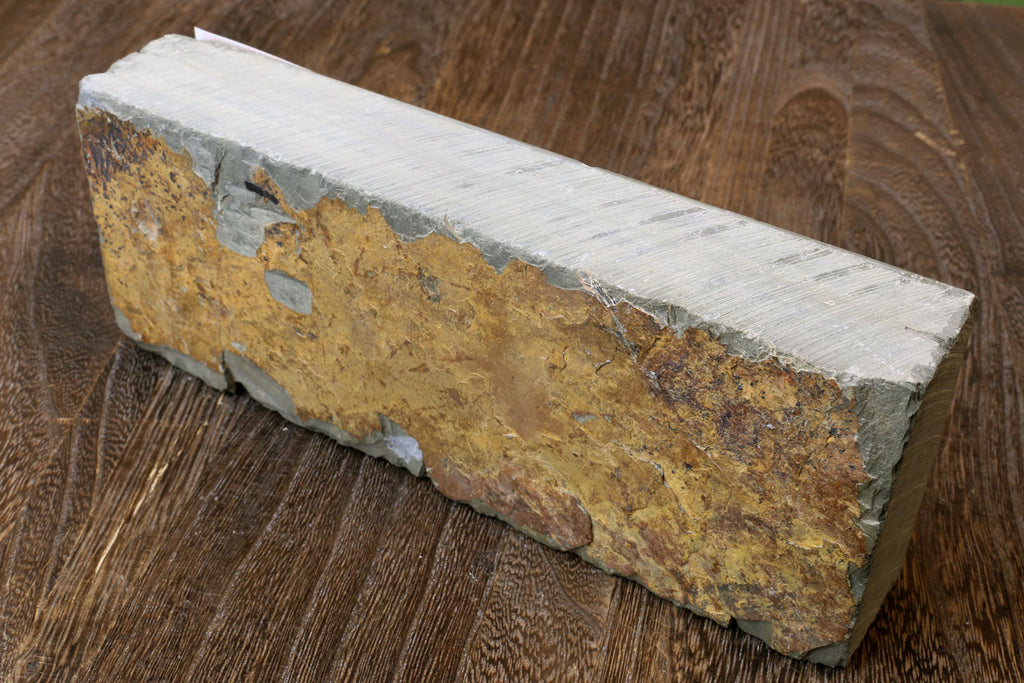 Natural whetstone block, yellow-brown with white sides, scuffed surface and chamfered ends.