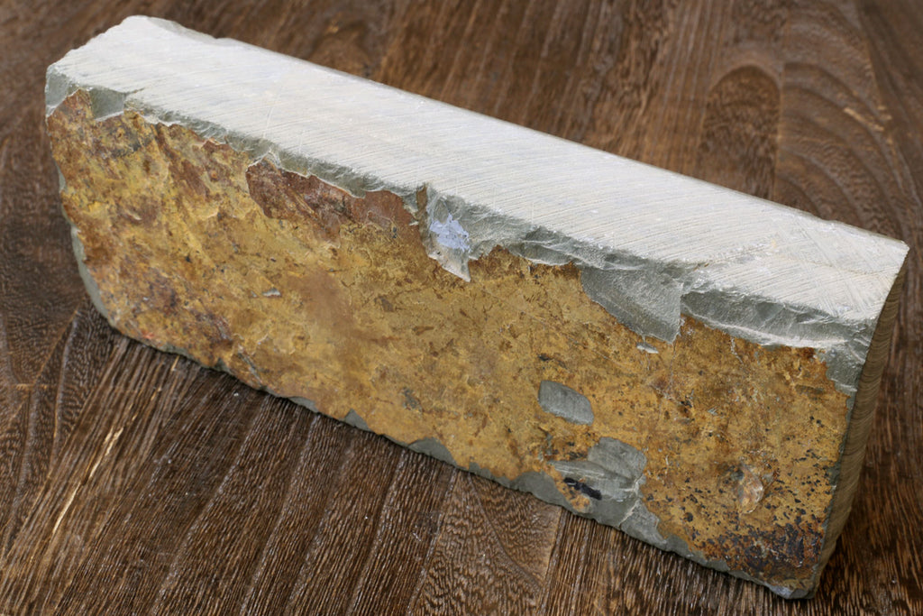 Natural whetstone block, yellow-brown core with white sides, worn mottled face.