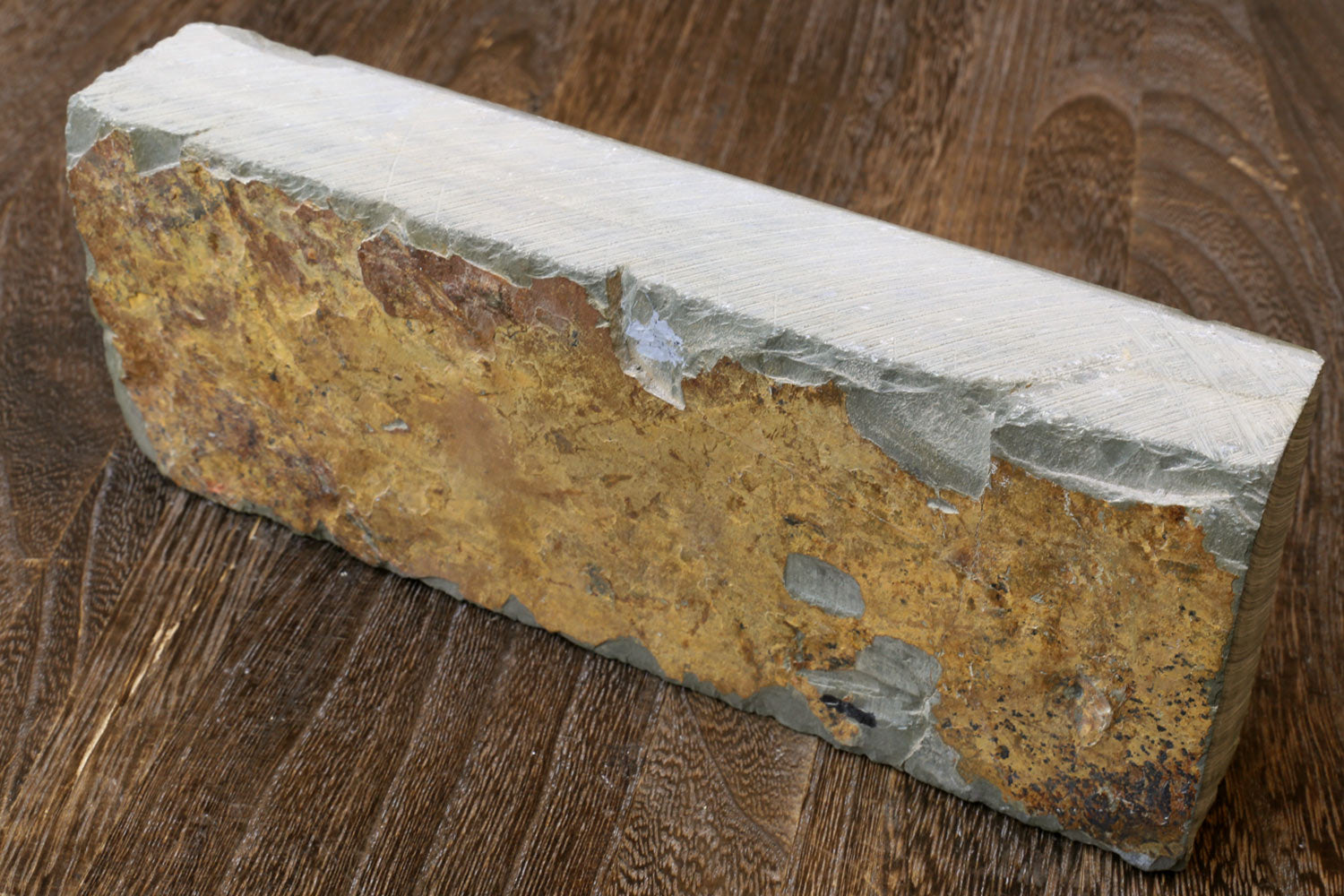 Natural whetstone block, yellow-brown core with white sides, worn mottled face.