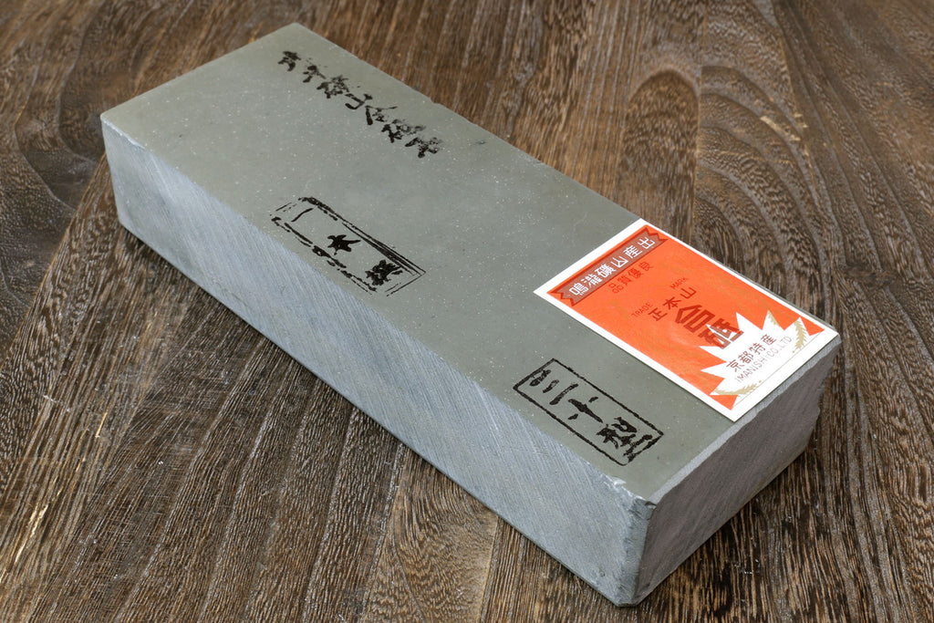 Natural sharpening whetstone with orange label and black markings on pale gray block