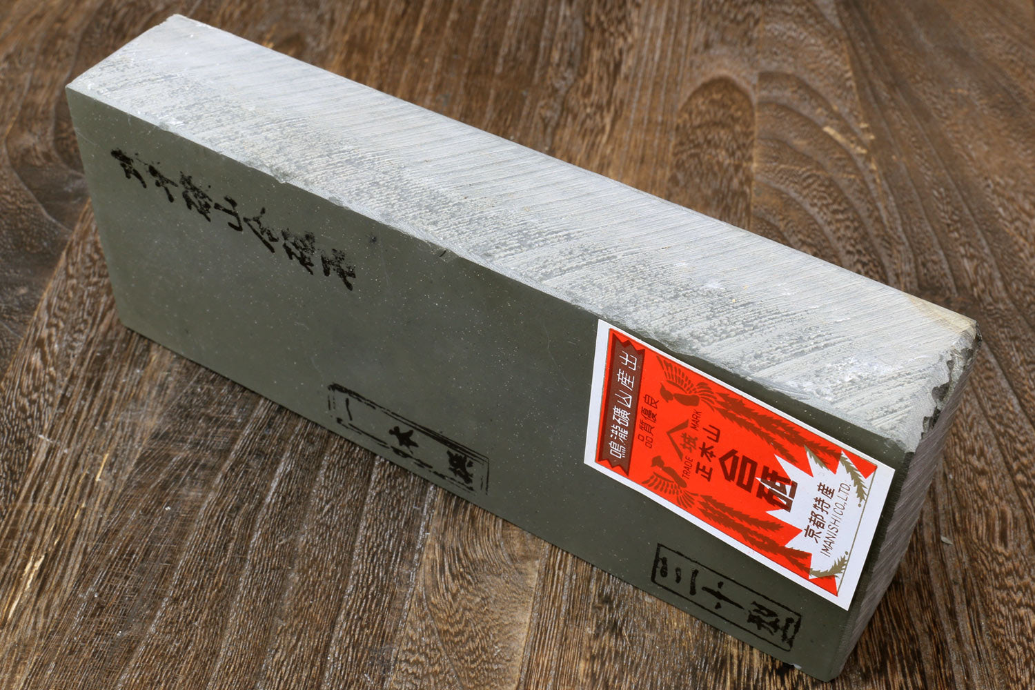 Natural sharpening whetstone with orange label and black text on end of pale gray block