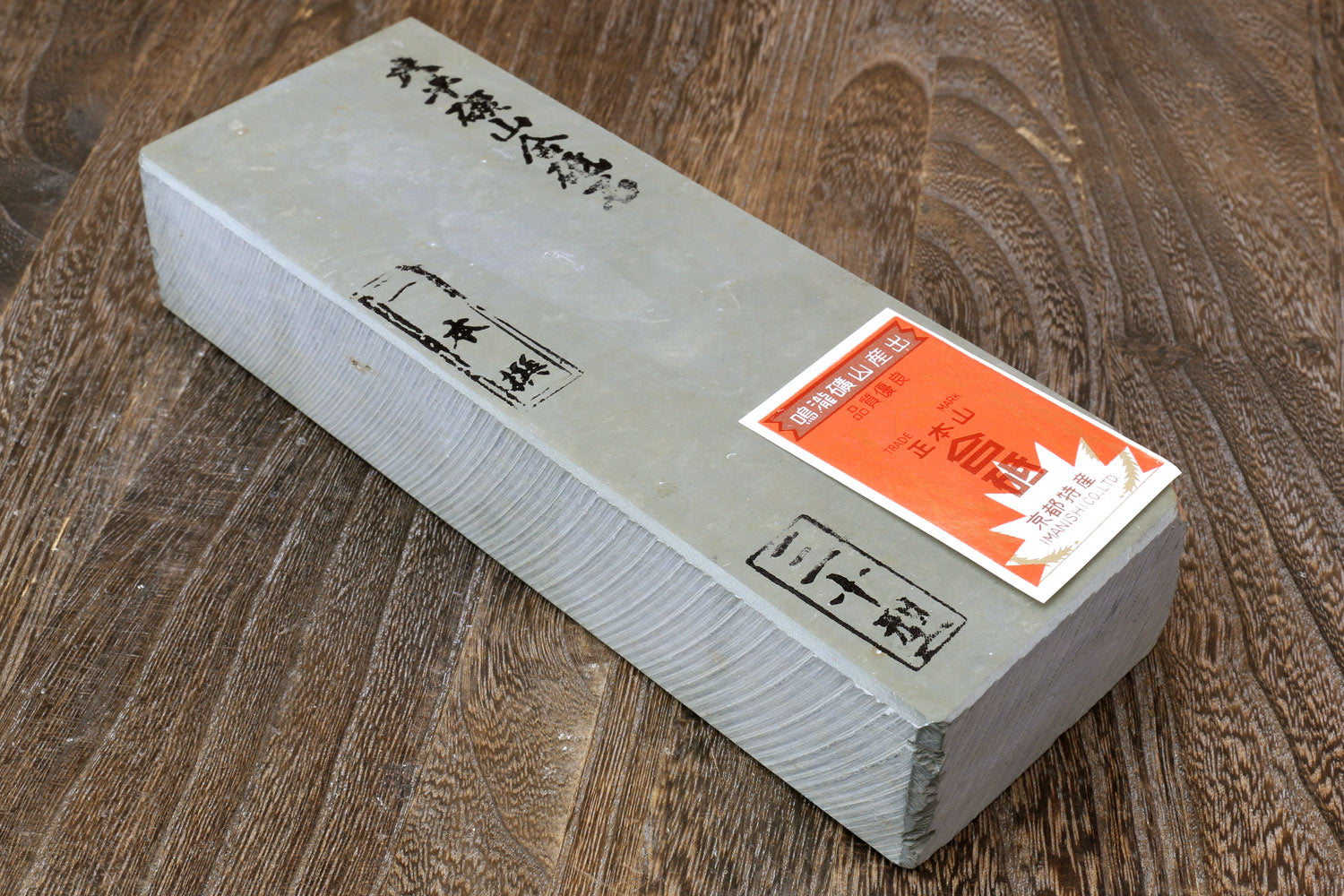 Natural whetstone block with printed text and orange-and-red label on the side