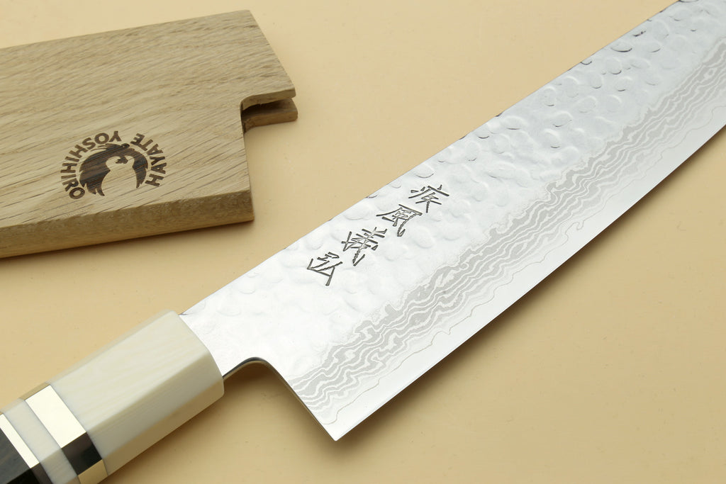 Japanese chef’s gyuto knife close-up with Damascus blade and white handle