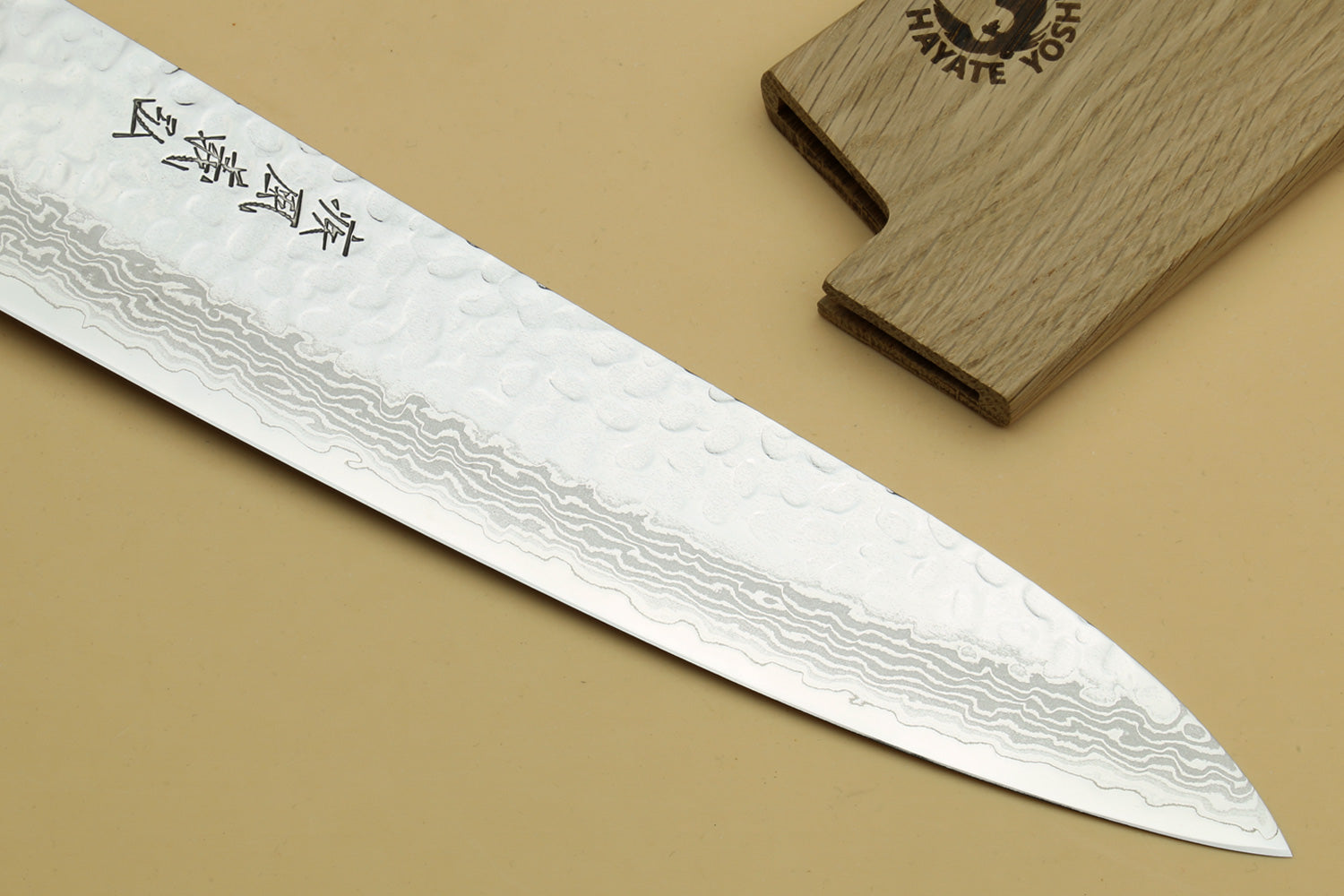 Japanese chef’s gyuto knife showing long Damascus blade edge and white handle