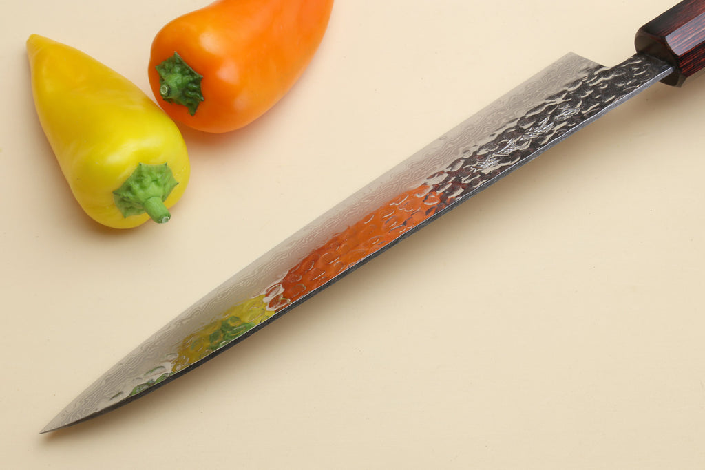 Damascus knife with dark handle and wavy etched blade near tip