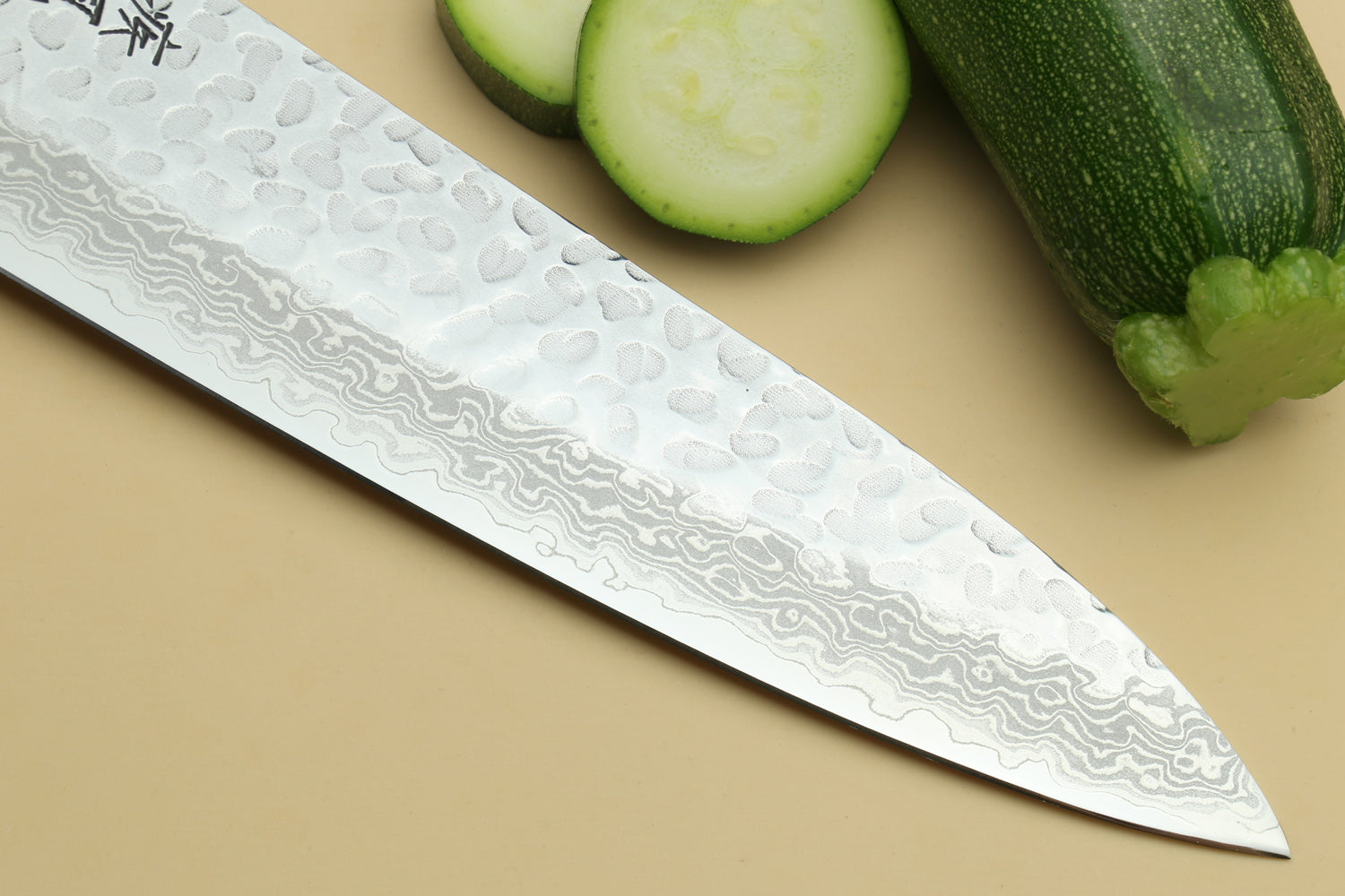 Chef's gyuto knife blade close-up with hammered Damascus pattern and turquoise octagonal handle