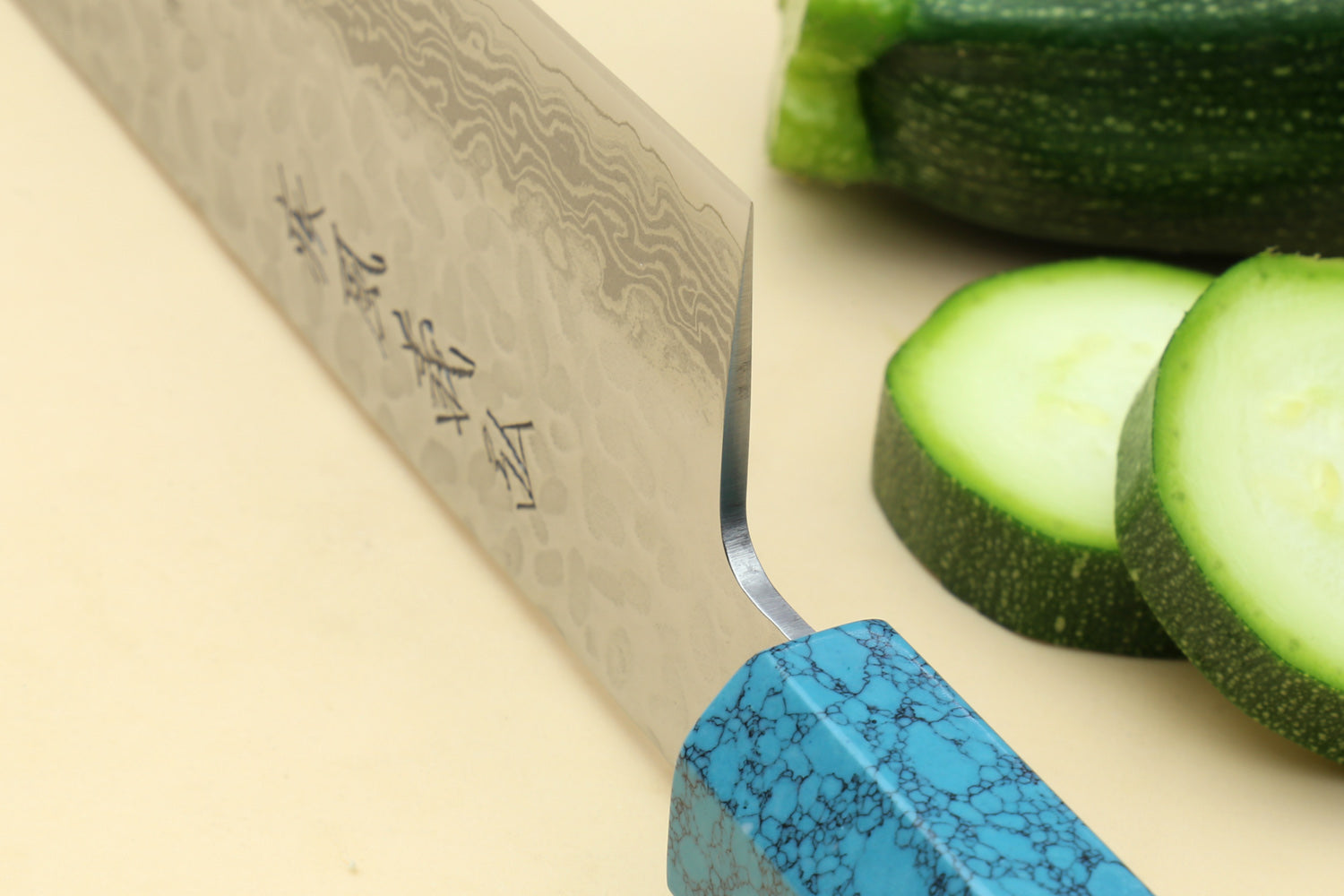Chef's gyuto knife heel close-up with hammered Damascus blade and turquoise octagonal handle