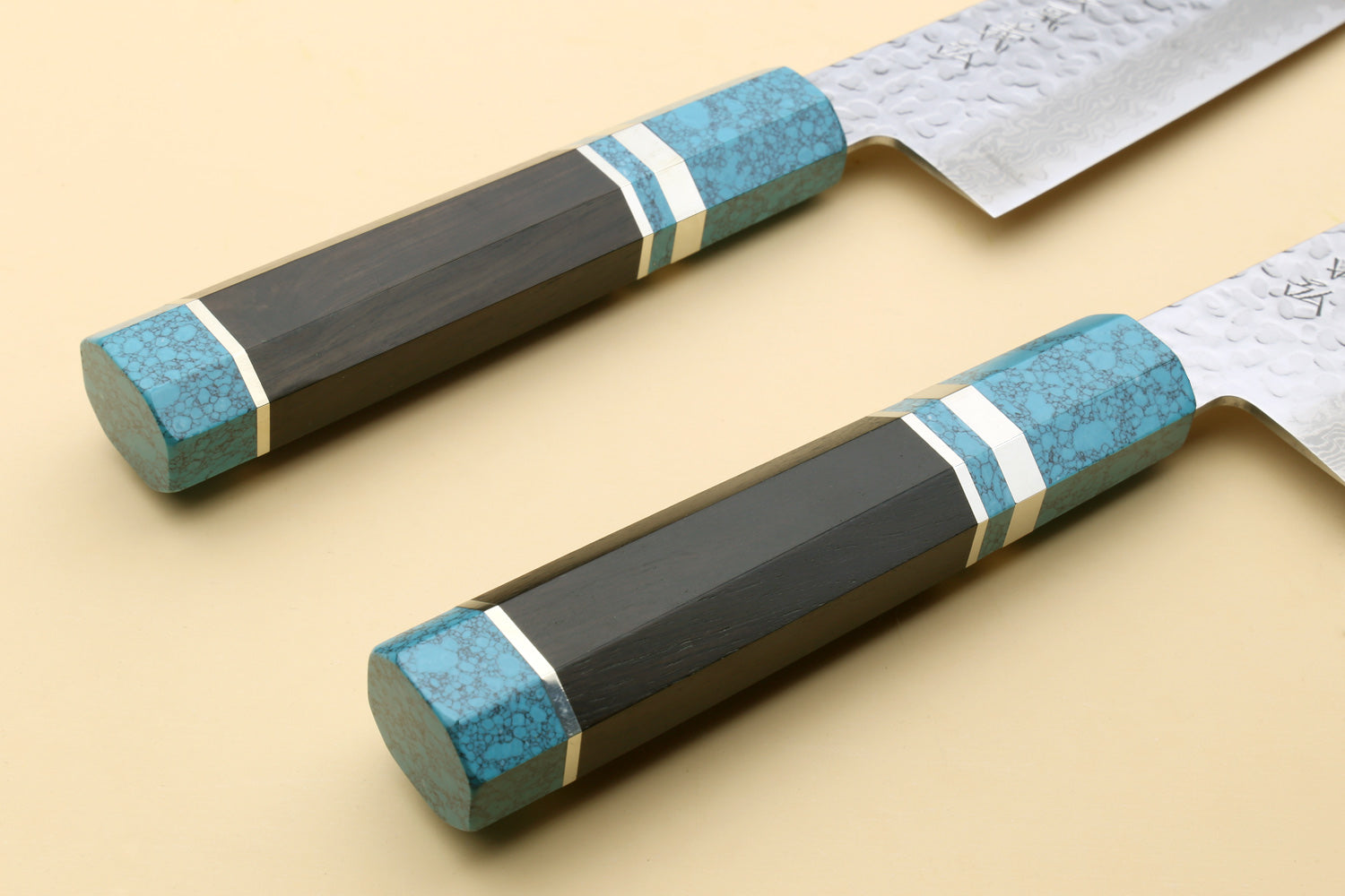 Two chef's gyuto knives with turquoise blue octagonal handles and hammered Damascus blades