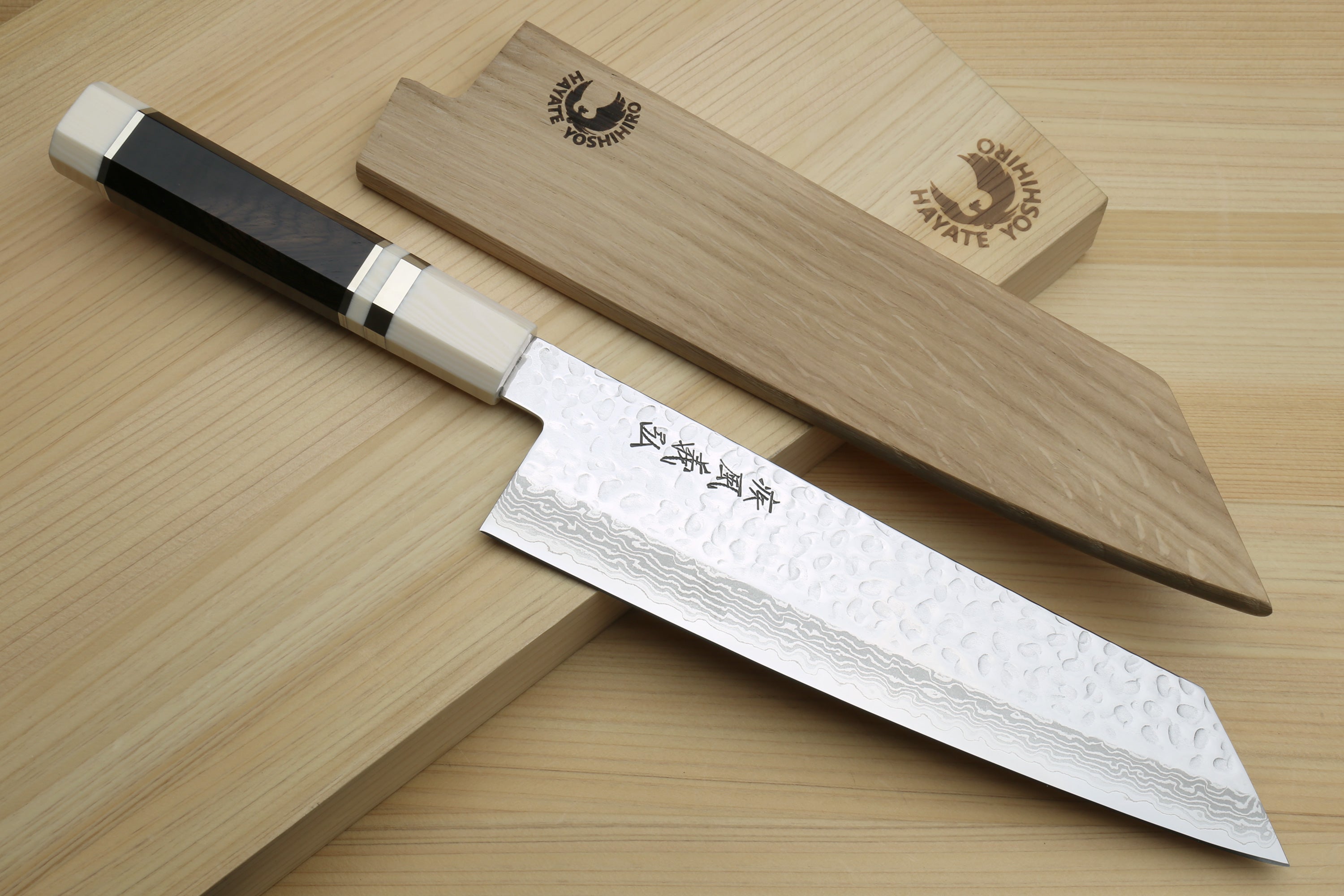 Kiritsuke chef knife showing hammered Damascus blade edge and octagonal ivory handle