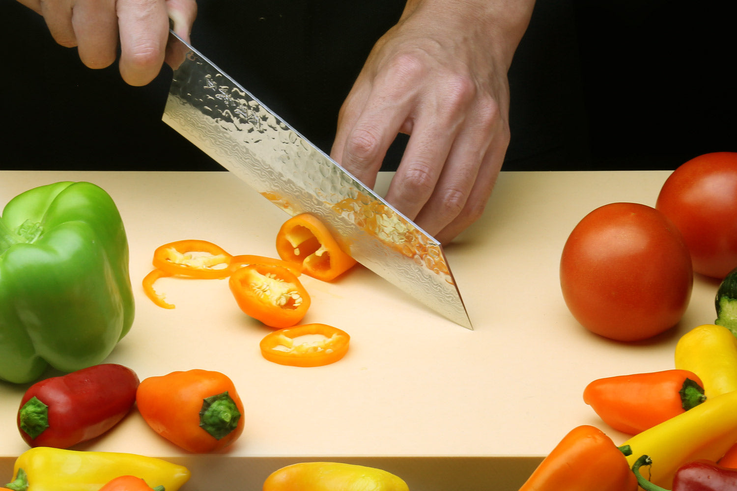 Kiritsuke Japanese chef knife with hammered Damascus blade held above a cutting surface