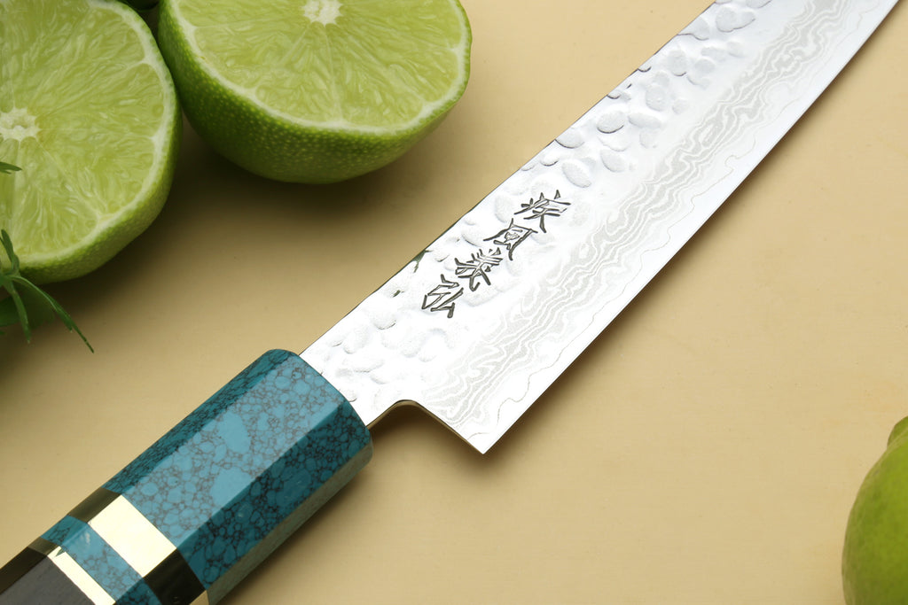 Damascus blade close-up with etched marks and turquoise blue handle.