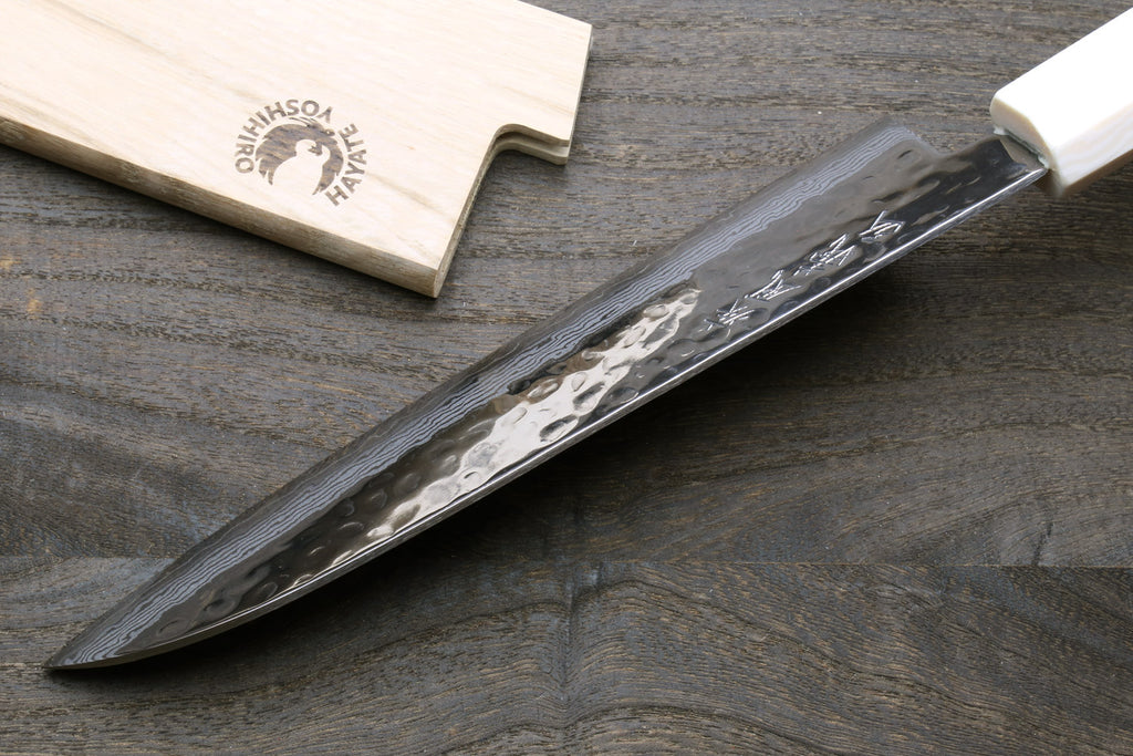 Damascus santoku knife on side angle with white howlite handle and ivory-toned bolster