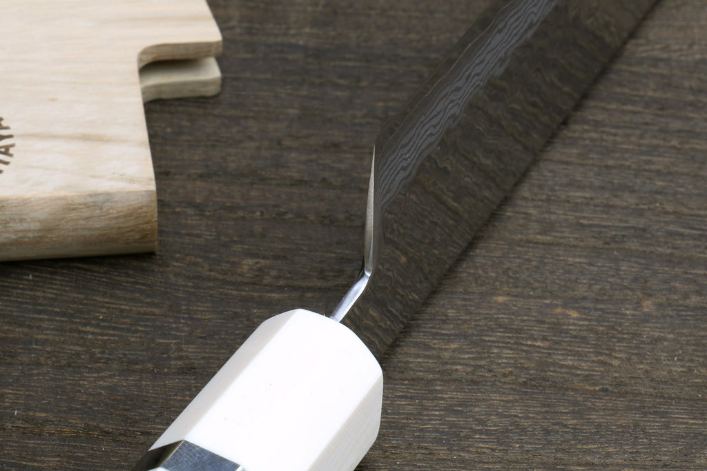 White howlite santoku handle with ivory-toned bolster and damascus blade edge close-up