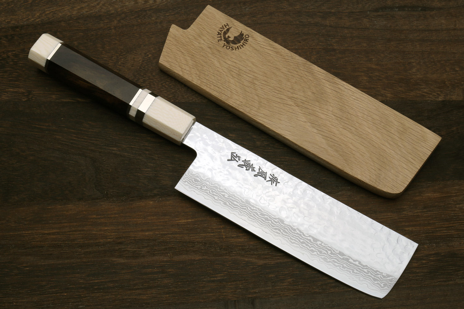 Nakiri knife with white damascus blade and dark handle; wooden saya and bolster detail