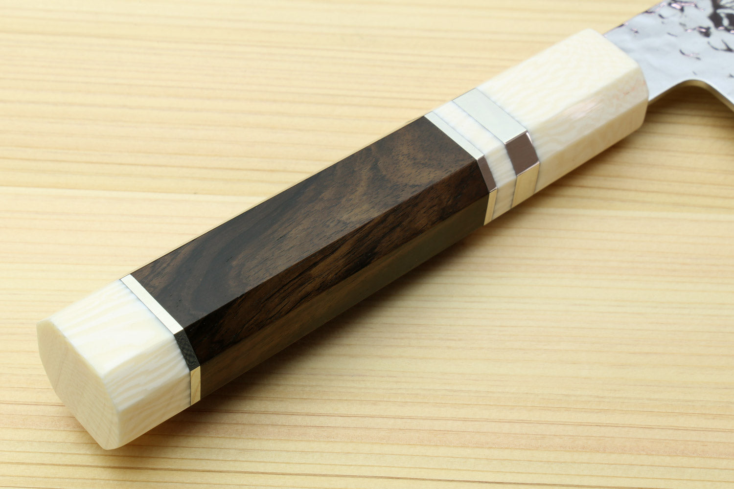 Nakiri knife side view with white hammered damascus blade and dark wood handle