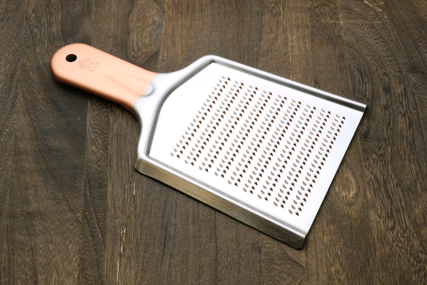 Radish grater with copper-toned handle and flat perforated grating plate