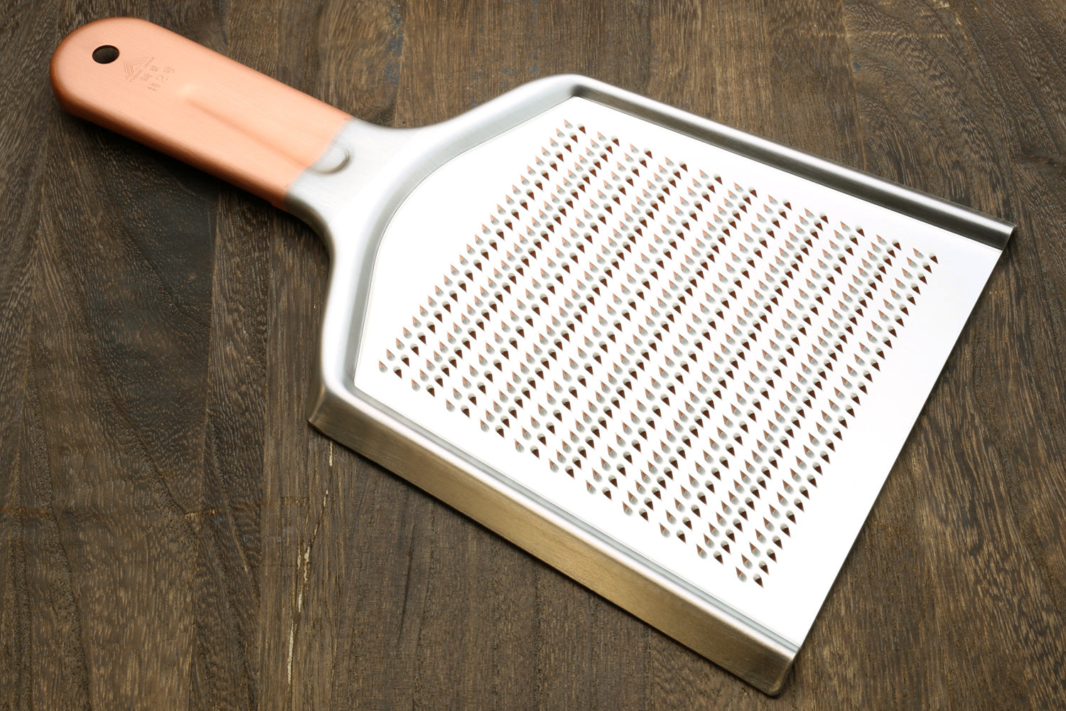 Radish grater with copper-toned handle and perforated metal grating plate