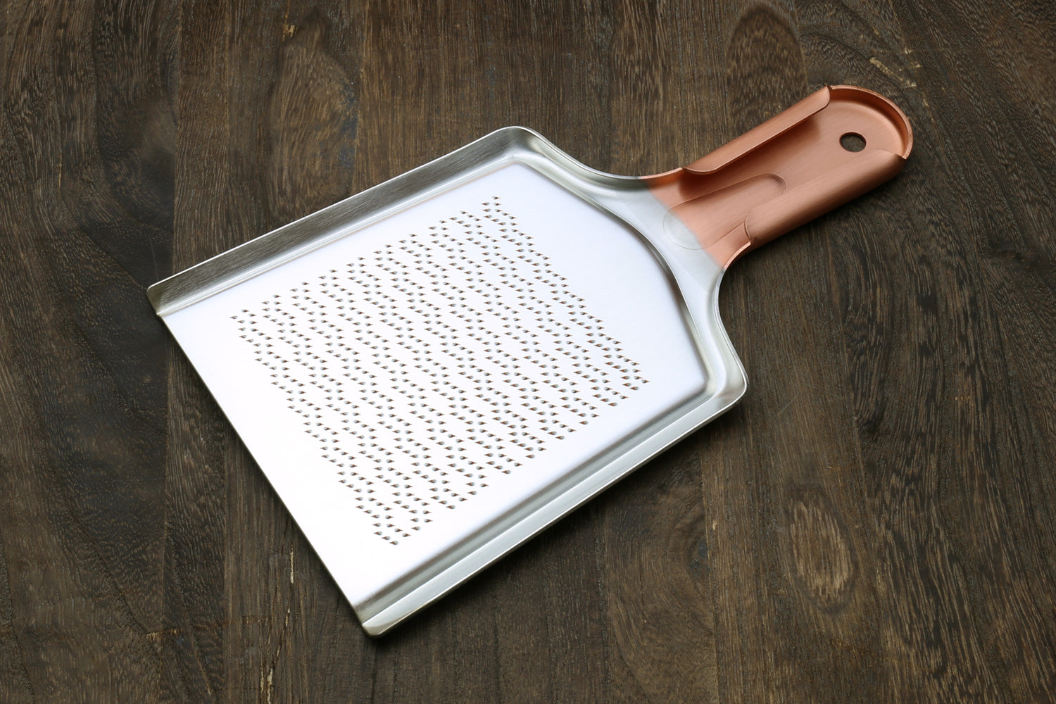 Radish grater with copper-toned handle and perforated grating face