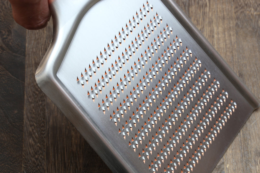 Radish grater showing perforated metal shredding pattern