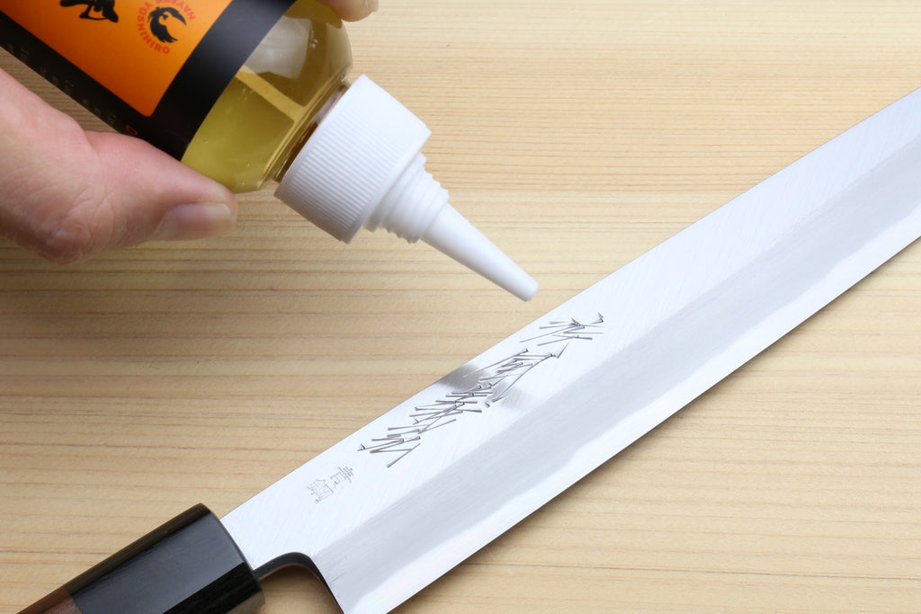 Knife oil care kit nozzle applying oil to a steel blade