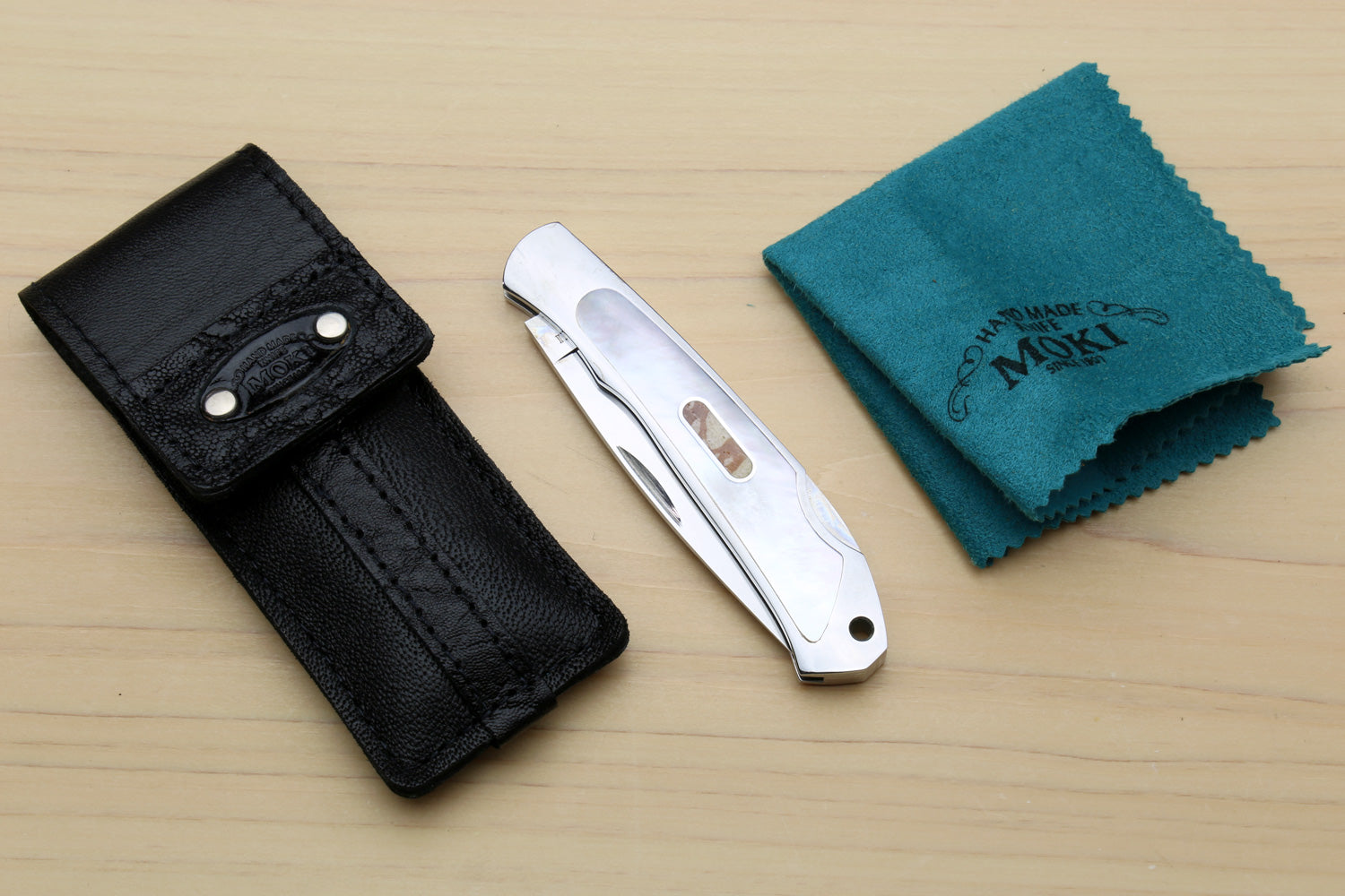 Lockback folding pocket knife with white handle, leather sheath and polishing cloth