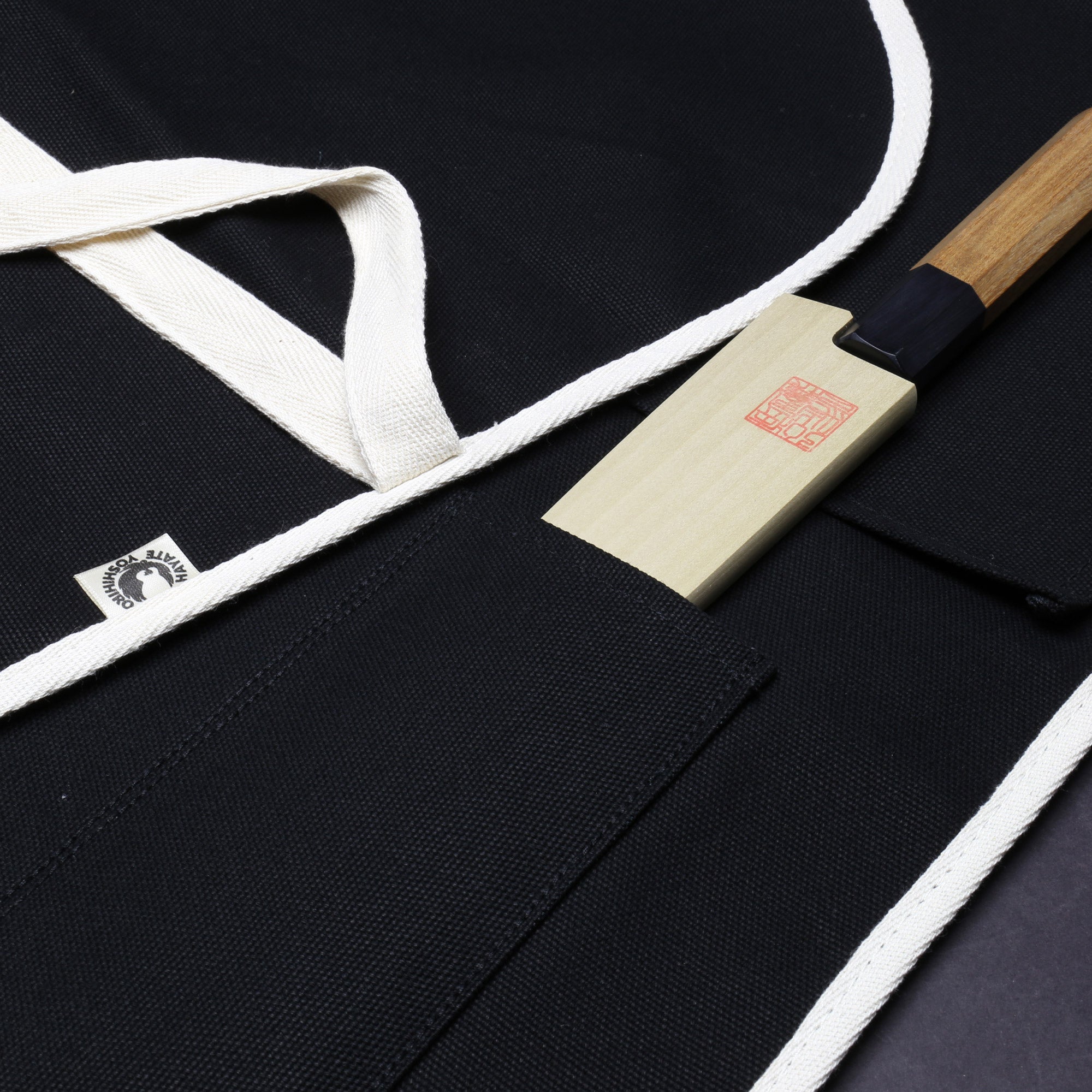 Close-up of black cotton knife pouch with white tie and beige label patch
