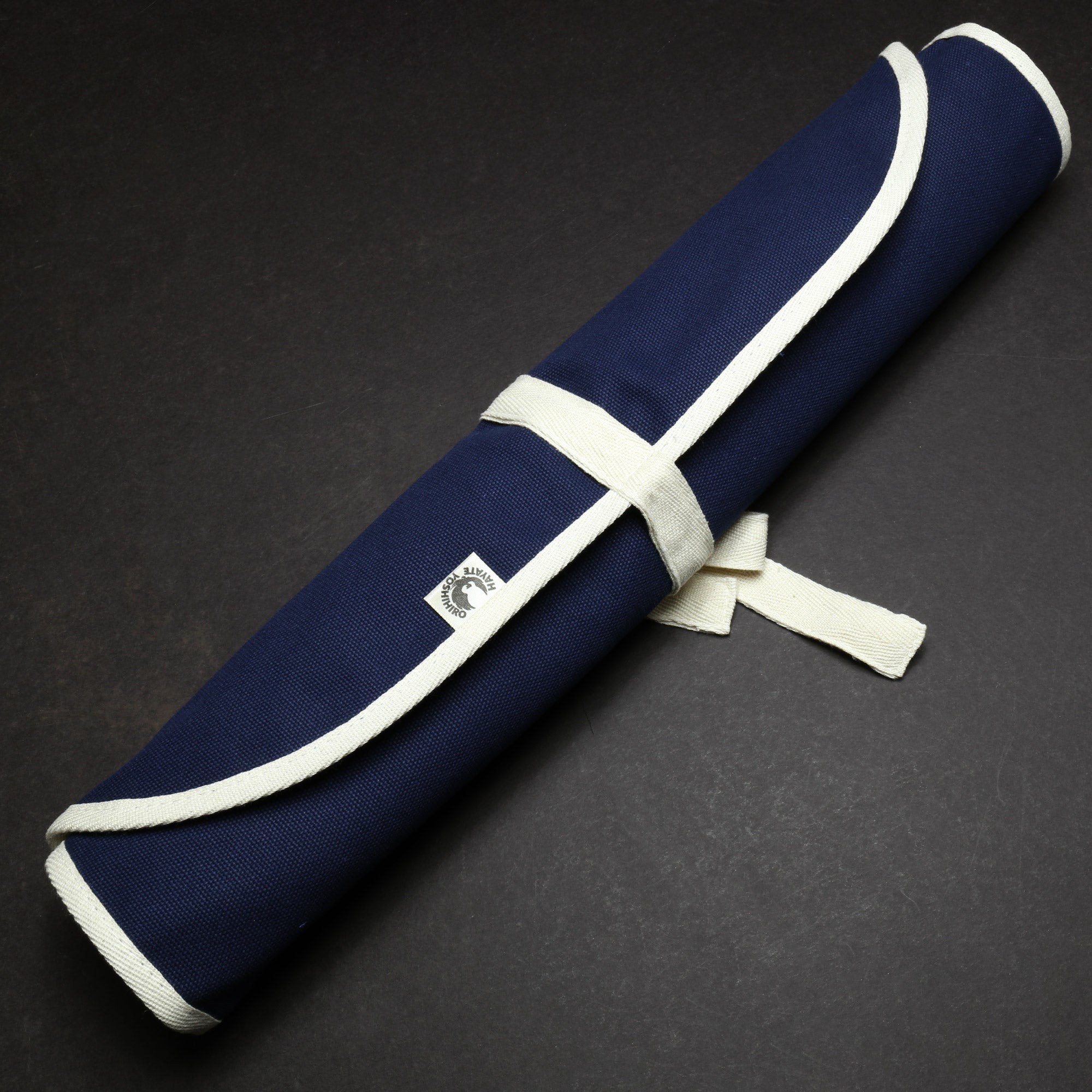 Dark navy cotton knife pouch bag, rolled and secured with a white wrap strap