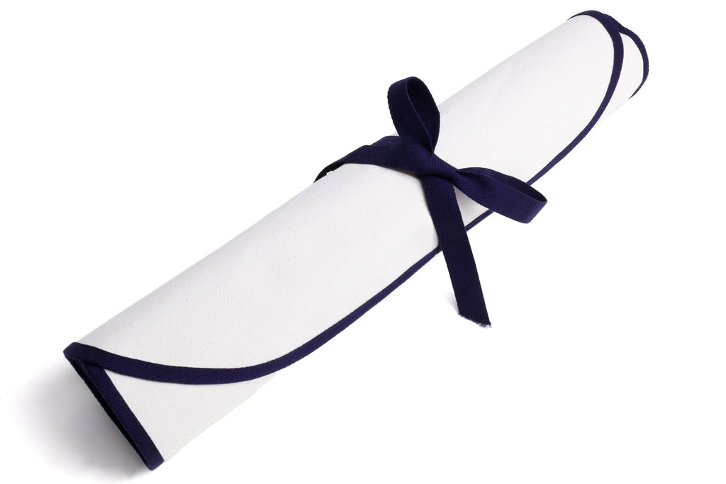 Rolled white knife pouch bag tied with navy ribbon and loop strap