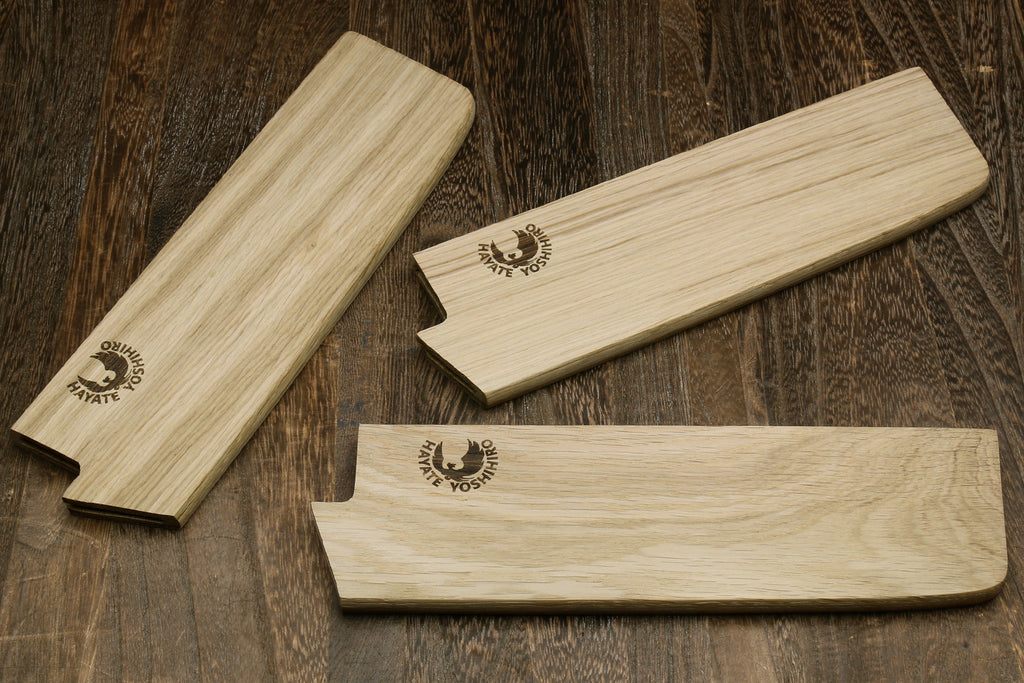 Multiple oak wood saya blade covers with embossed logos, shown laid out