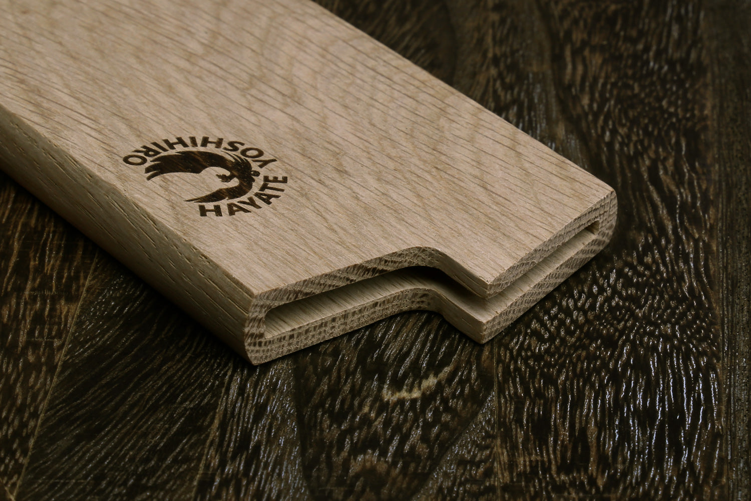 Oak wood saya blade cover with stepped edge and embossed logo, angled view