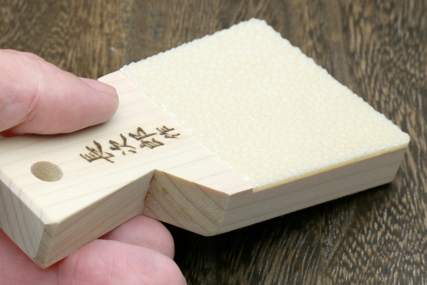 Japanese sharkskin grater block held in hands, white textured surface with logo