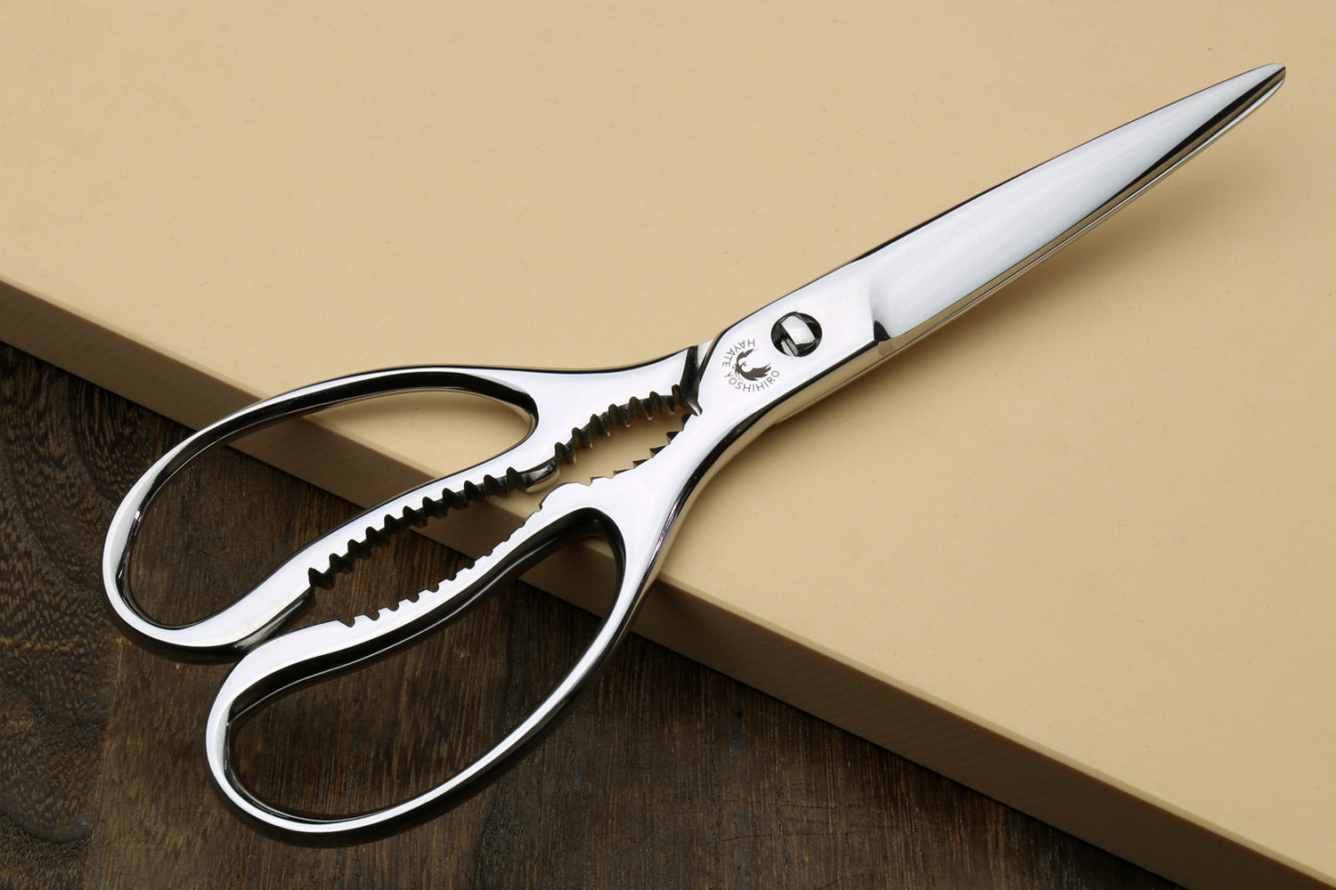Large stainless kitchen shears with white handles and serrated lower blade
