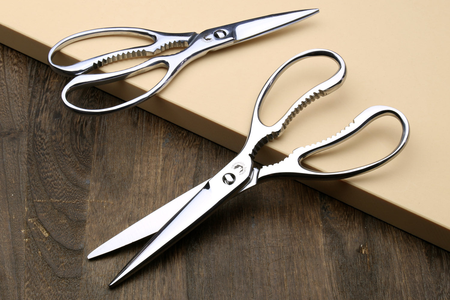 Stainless kitchen scissors with white handles, pointed blades and serrated grip