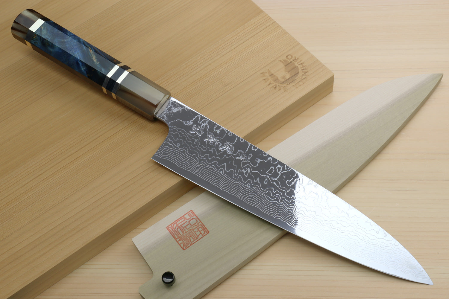 Chef knife with patterned Damascus blade, ocean blue handle, and white side panel