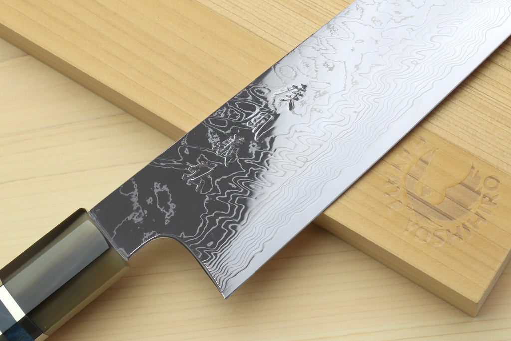 Kiritsuke chef knife with Damascus blade and ocean blue handle, angled view on wood