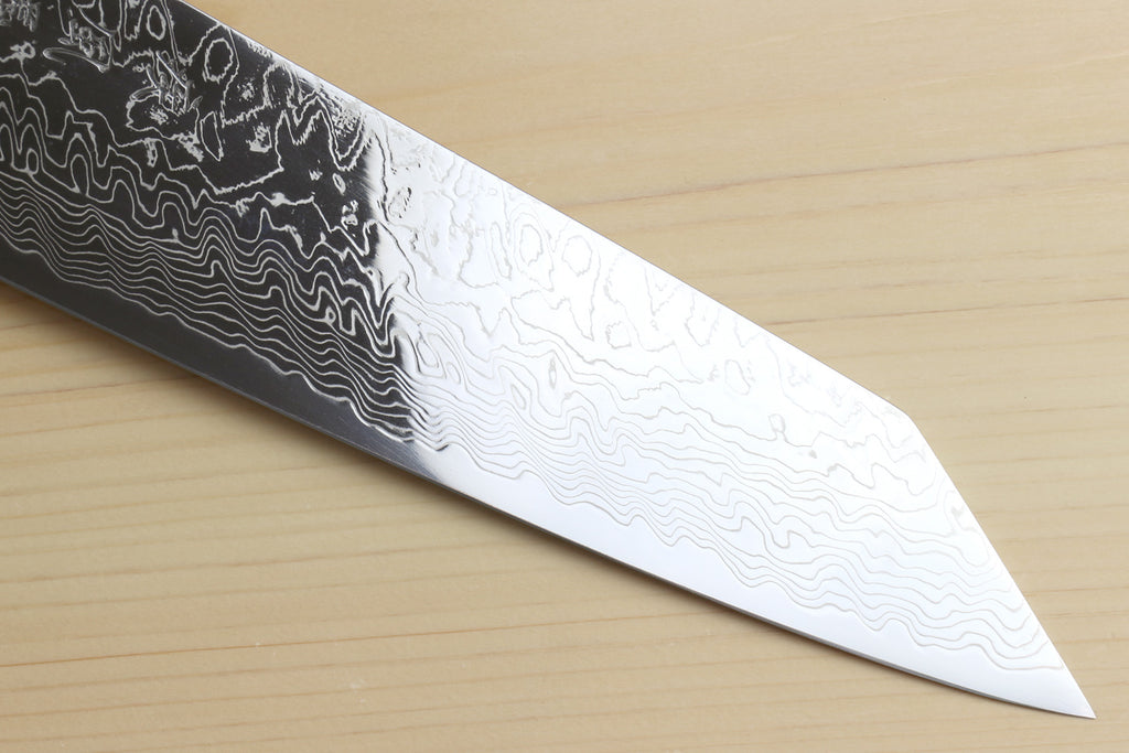 Kiritsuke chef knife blade close-up with wavy Damascus pattern and pointed tip