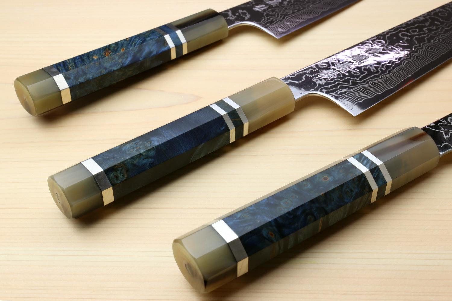 Kiritsuke chef knife with ocean blue handle and Damascus blade, multiple knives shown