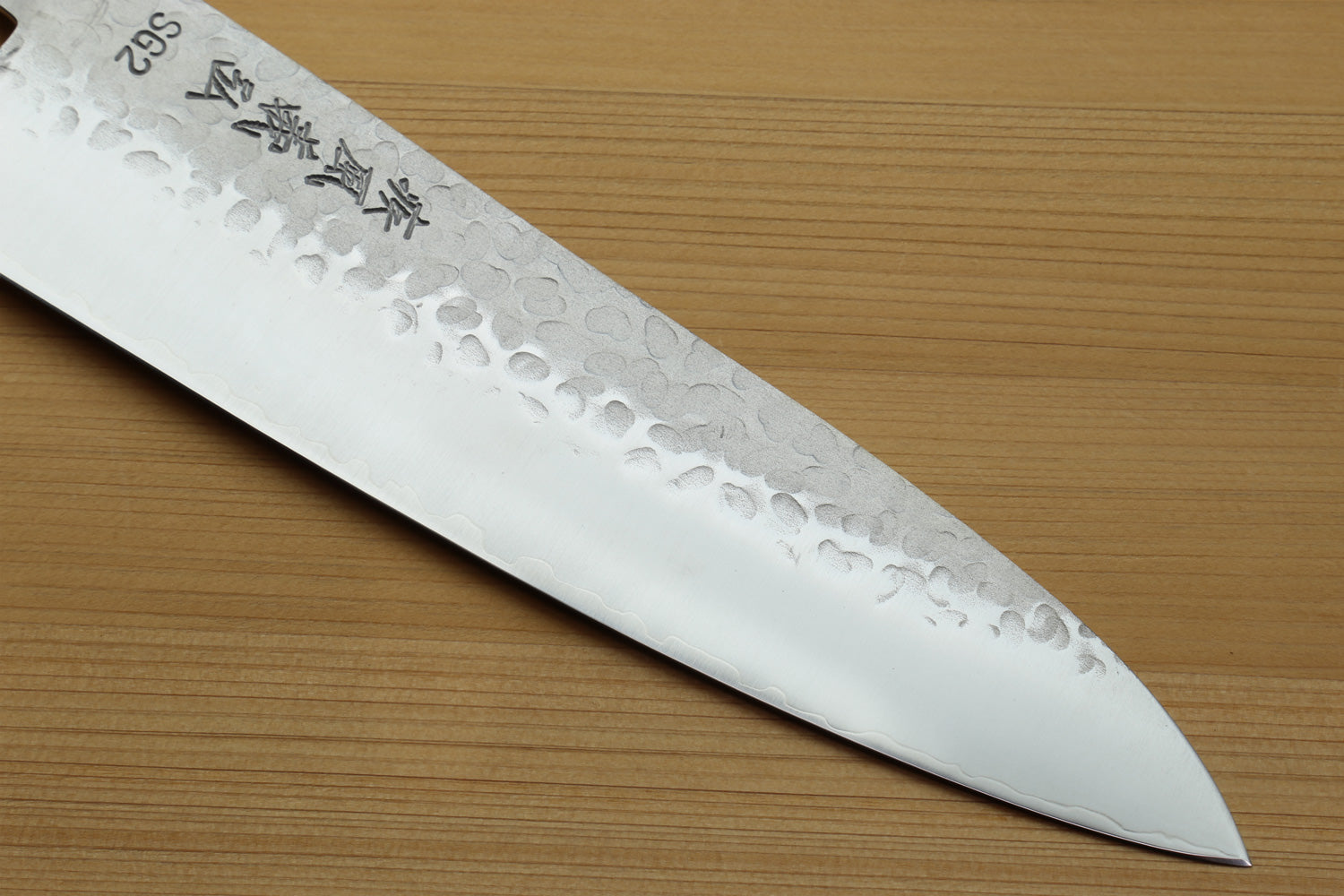 Hammered stainless gyuto knife blade with textured pattern and tapered edge