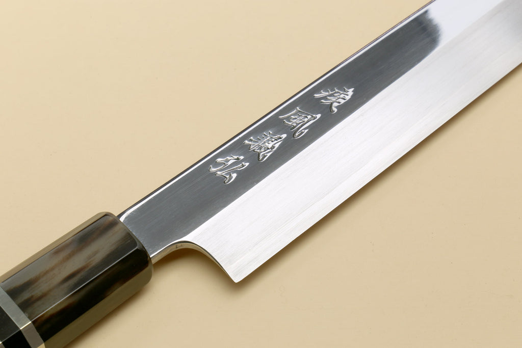 Yanagi sashimi knife showing engraved blade and dark triple-ring ebony handle