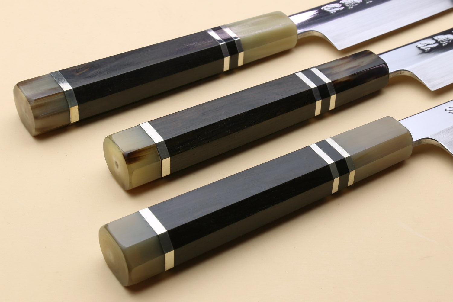 Two yanagi sashimi knives with dark triple-ring ebony handles and mirror-polished blades