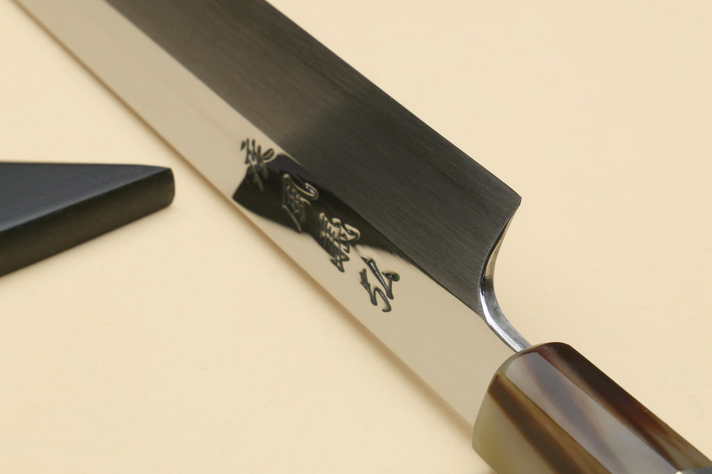 Yanagi kiritsuke knife end view with engraved blade and dark handle