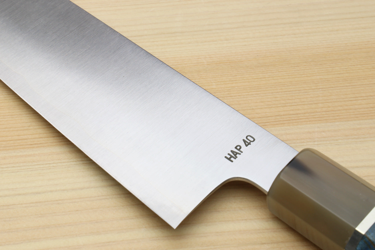 Stainless steel gyuto chef knife blade showing HAP40 stamp and bolster