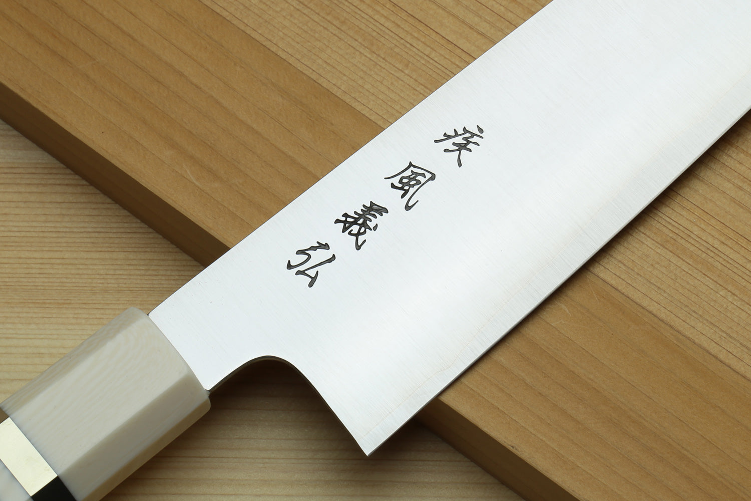 Kiritsuke chef's knife with stainless steel blade and white bolster near the handle