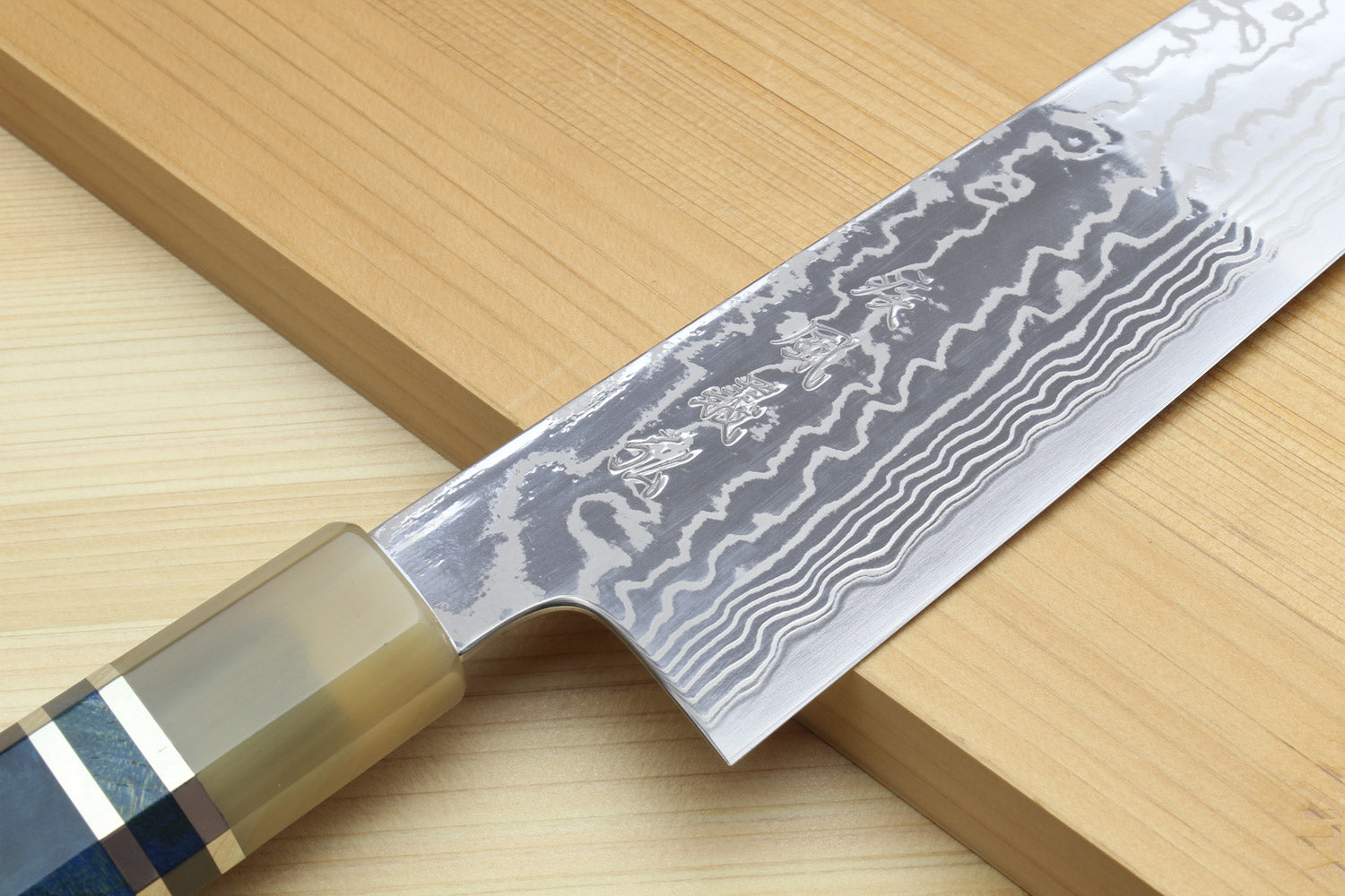 Kiritsuke chefs knife showing damascus blade pattern and blue handle