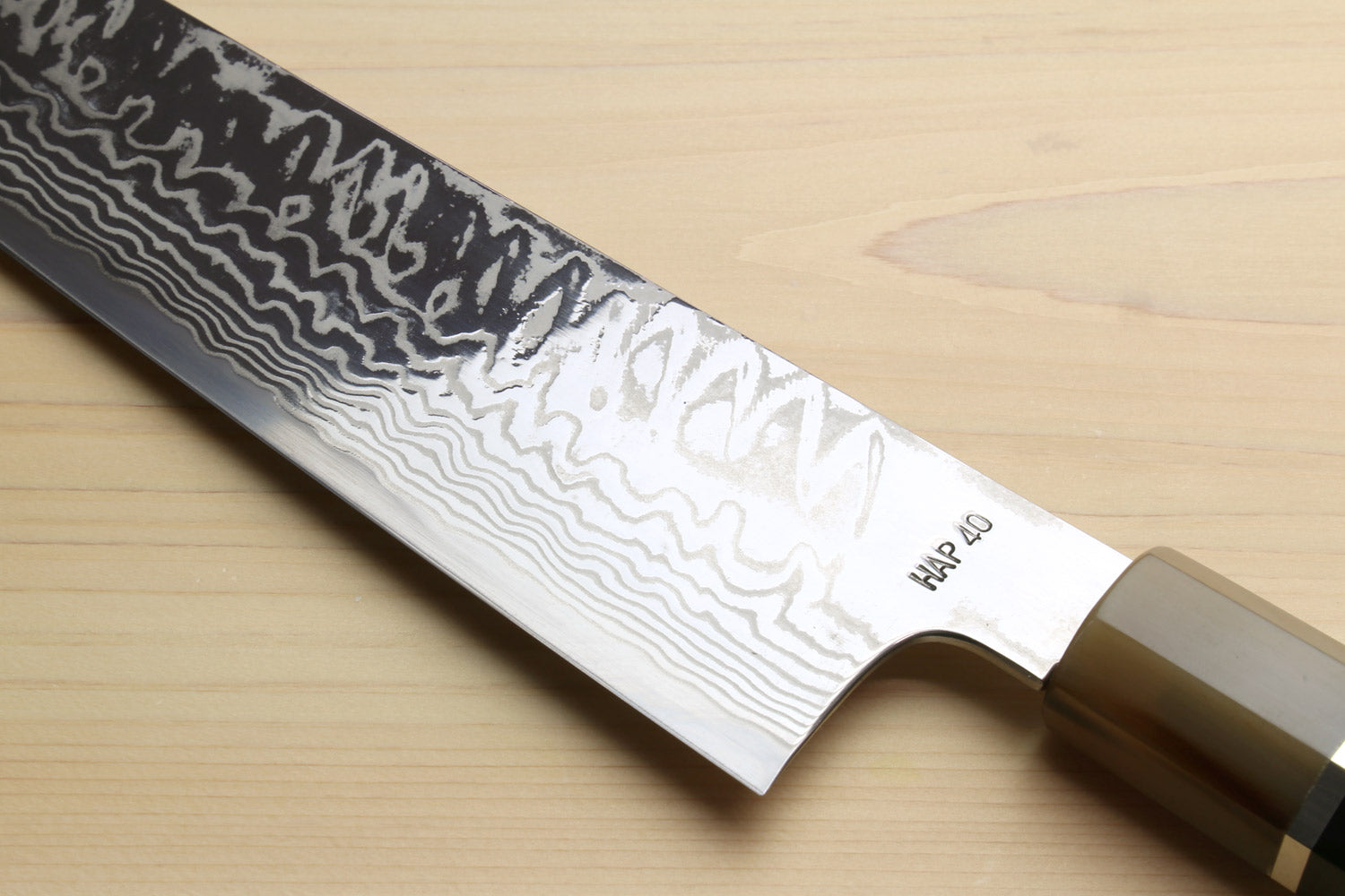 Kiritsuke chef's knife, wavy damascus blade with dark handle and stainless bolster